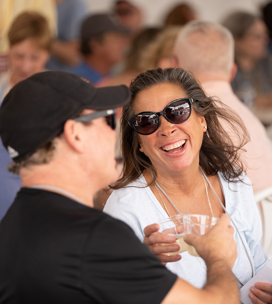 Couple smiling and toasting beer in VIP tent
